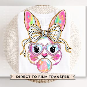 May include: A white t-shirt with a colorful bunny rabbit wearing heart-shaped sunglasses and a black and white polka dot bow. The bunny is blowing a bubble. The text "DIRECT TO FILM TRANSFER" is printed at the bottom of the shirt.