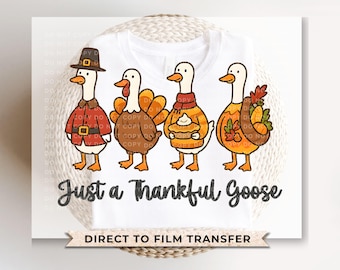 Op de afbeelding: Wit T-shirt met een grillige illustratie van vier ganzen gekleed in Thanksgiving-kleding. De ganzen dragen een pelgrimshoed, kalkoenveren, een sjaal en houden herfstbladeren en een taart vast. De tekst "Just a Thankful Goose" staat eronder.