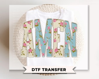 May include: White t-shirt with the word "AMEN" in a floral design. The letters are outlined with a pearl-like trim. The floral pattern includes pink roses and blue accents. The text "DTF TRANSFER" is at the bottom.