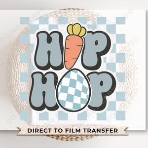 May include: A blue and white checkered Easter egg with a carrot and the words "Hip Hop" in blue with black outlines. The image is on a white background with a blue and white checkered pattern.