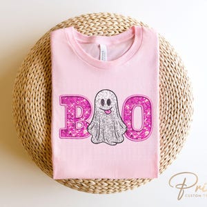 May include: Pink t-shirt with a sparkly pink "BOO" and a sparkly silver ghost with a pink smile.