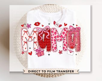 Peut inclure: T-shirt blanc avec le mot "MAMA" dans un design de la Saint-Valentin. Les lettres sont décorées de nœuds, de cœurs et de motifs rouges et roses. Le design comprend des cœurs, des fleurs et des boîtes cadeaux.
