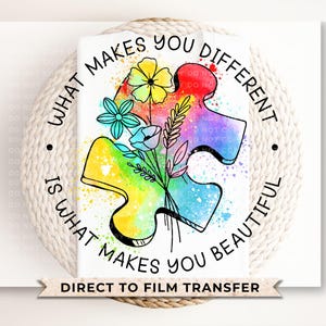 May include: A colorful puzzle piece with a rainbow design and flowers. The text "What makes you different is what makes you beautiful" is written around the puzzle piece. Direct to film transfer.