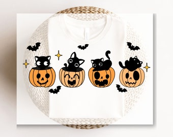 May include: A white t-shirt with a design of four black cats sitting inside orange jack-o'-lantern pumpkins. The pumpkins have spooky faces and there are stars and bats around them.