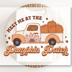 May include: A white t-shirt with a vintage-style graphic of a pickup truck filled with pumpkins. The text "Meet me at the Pumpkin Patch" is written in a retro font.