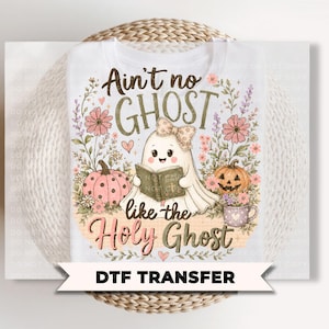 May include: A white DTF transfer featuring a cartoon ghost wearing a bow and reading a book, surrounded by pink pumpkins, flowers, and a mug. The text reads Ain't no GHOST like the Holy Ghost. The design includes soft pastel colors and floral accents.