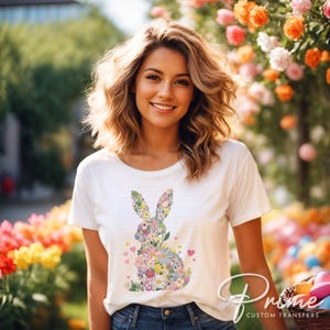 Op de afbeelding: Een wit T-shirt met een bloemig konijnontwerp. Het konijn is gemaakt van kleurrijke bloemen en bladeren. Er zijn ook kleine roze hartjes rond het konijn.