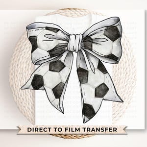 May include: A black and white watercolor illustration of a bow made from a soccer ball pattern. The bow is tied with a white ribbon. The image has the text "DIRECT TO FILM TRANSFER" at the bottom.