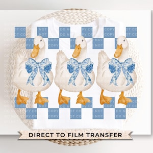 May include: Three white ducks with blue and white ribbon bows on their necks. The ducks are standing on a white background with a blue and white checkered pattern.