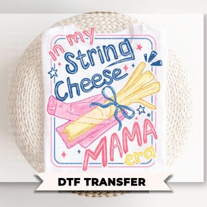 May include: White t-shirt with a colorful graphic that reads "In my String Cheese Mama Era." The design features a bundle of string cheese tied with a blue bow, and a pink package. The words are in blue, pink, and yellow.
