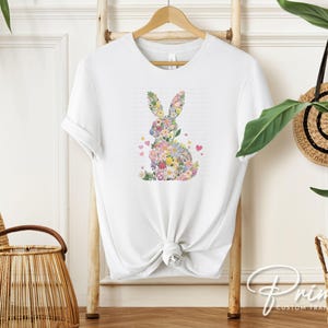 Op de afbeelding: Wit T-shirt met een bloemenkonijn-silhouetontwerp. Het konijn is gemaakt van kleurrijke bloemen en bladeren.