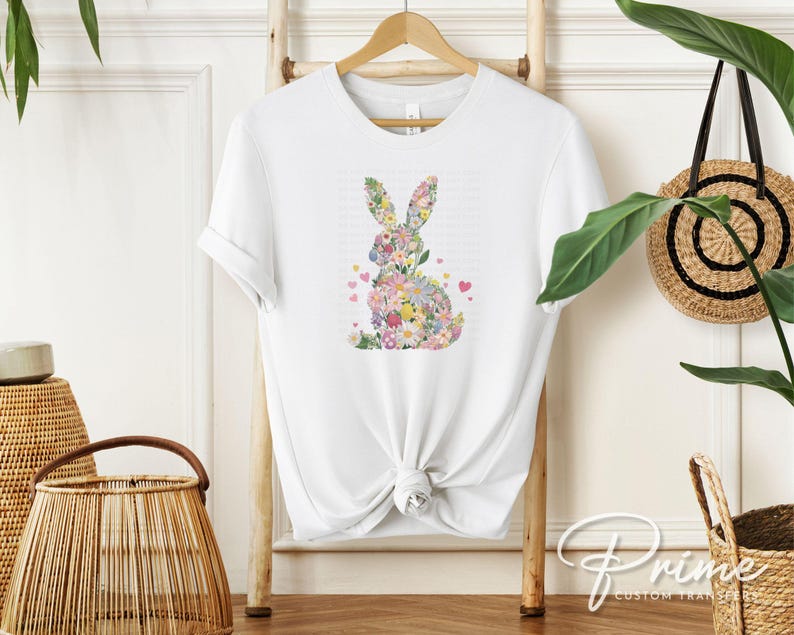 Op de afbeelding: Wit T-shirt met een bloemenkonijn-silhouetontwerp. Het konijn is gemaakt van kleurrijke bloemen en bladeren.