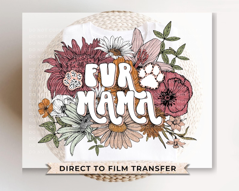 May include: White t-shirt featuring the text "FUR MAMA" in a retro font, surrounded by a floral design with pink, orange, and green flowers. A paw print is incorporated into the design. The words "DIRECT TO FILM TRANSFER" are at the bottom.