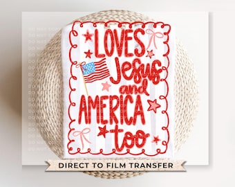 May include: A white and red graphic design featuring the text "LOVES Jesus and AMERICA too" with an American flag illustration. The design includes red stars and bows. The words are in a playful, handwritten style.
