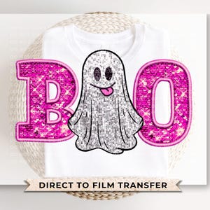 May include: A white t-shirt with a pink sparkly "BOO" and a ghost graphic. The ghost is white with a pink mouth and eyes. The text "DIRECT TO FILM TRANSFER" is at the bottom of the shirt.