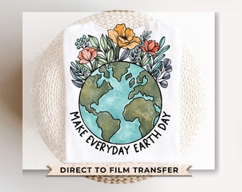 以下が含まれることがあります： 花に囲まれた地球のカラフルなイラストが描かれた白いTシャツ。地球の周りに「Make Every Day Earth Day」という文字が書かれています。このTシャツはダイレクト・トゥ・フィルム・トランスファーです。