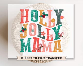 May include: A white t-shirt featuring a colourful design that reads "Holly Jolly Mama" in a retro style. The design incorporates red, green, pink and yellow colours. The text "Direct to Film Transfer" is printed beneath the design.
