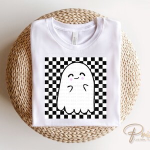 May include: White t-shirt with a black and white checkered pattern and a cute ghost with pink cheeks in the center.