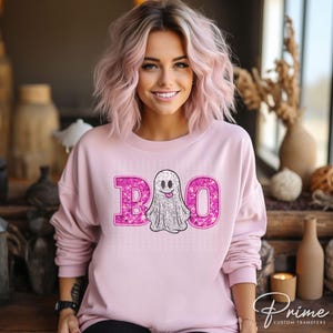 May include: Pink sweatshirt with a sparkly pink "BOO" with a ghost in the middle. The ghost is white with a smiling face and a tongue sticking out.