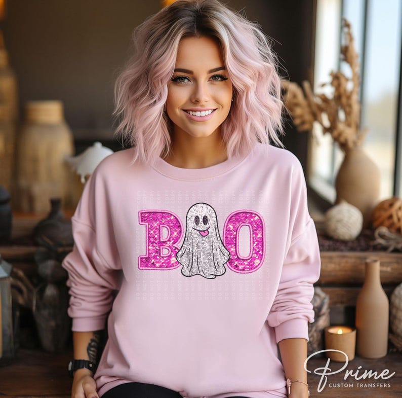 May include: Pink sweatshirt with a sparkly pink "BOO" with a ghost in the middle. The ghost is white with a smiling face and a tongue sticking out.