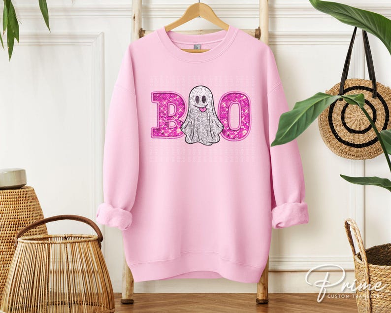 May include: Pink sweatshirt with a sparkly pink "BOO" and a white ghost with a pink smile.