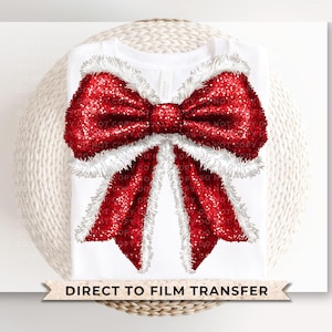 May include: A white t-shirt with a large red glitter bow with white trim. The text "DIRECT TO FILM TRANSFER" is printed at the bottom of the shirt.