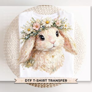 Op de afbeelding: Wit T-shirt met een aquarel illustratie van een konijn met een bloemenkrans. Het konijn heeft lange oren en een lieve uitdrukking. De tekst "DTF T-SHIRT TRANSFER" staat onderaan.