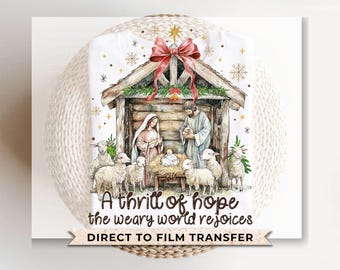 May include: A watercolor illustration of a nativity scene with a wooden manger, a baby Jesus, Mary, Joseph, and sheep. The text "A thrill of hope the weary world rejoices" is written below the scene. "Direct to Film Transfer" is written below the text.