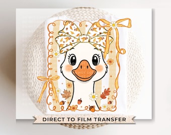 May include: A white cartoon goose with a large bow featuring autumn leaves and acorns. The goose has a peach-colored beak and cheeks, surrounded by a decorative border with fall-themed accents. The text "DIRECT TO FILM TRANSFER" is at the bottom.