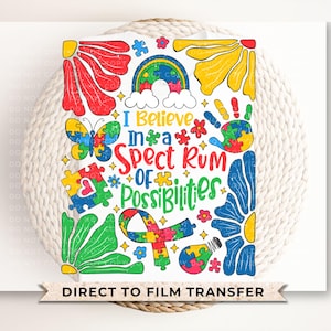 May include: A colorful graphic design with a rainbow puzzle piece pattern and the text "I Believe in a Spectrum of Possibilities". The design includes a butterfly, a handprint, and flowers.