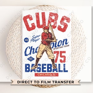 May include: A vintage-style baseball graphic with the text "CUBS" in red, "Champion Sporting Team" in blue, and "Baseball" in red. The graphic also includes a baseball player in a red and white uniform, the text "CHI" and "ESTD 1975" in blue, and the number "75" in red. The text "Direct to Film Transfer" appears at the bottom of the graphic.