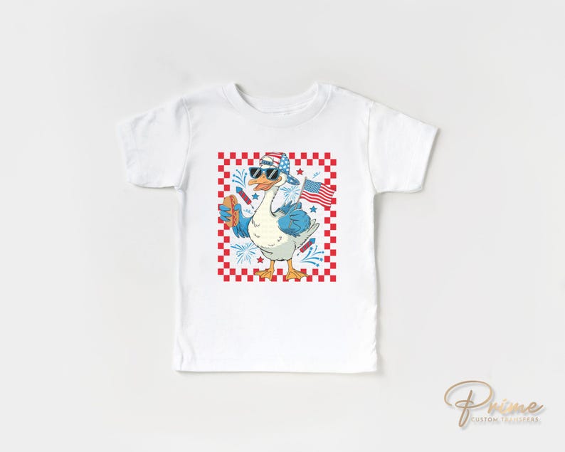 K&ouml;nnte beinhalten: Wei&szlig;es T-Shirt mit einem rot-wei&szlig;-blauen karierten Hintergrund. Eine Cartoon-Gans mit Sonnenbrille und einem rot-wei&szlig;-blauen Hut h&auml;lt einen Hotdog und eine kleine amerikanische Flagge. Der Text "Prime Custom Transfers" befindet sich in der rechten unteren Ecke.