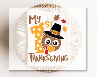 May include: White babygrow with a brown turkey wearing a black hat and the text "My 1st Thanksgiving" in brown letters.