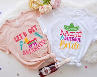 May include: Two white t-shirts with a pink t-shirt on top. The white shirts have the text "Nacho Average Bride" and the pink shirt has the text "Let's Get Smashed".