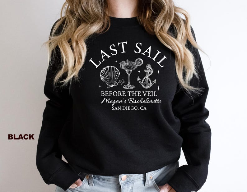 May include: Black sweatshirt with white text and nautical-themed graphics. The text reads "LAST SAIL BEFORE THE VEIL Megan's Bachelorette SAN DIEGO, CA." Graphics include a seashell, cocktail, and anchor. The word "BLACK" is printed on the left side.