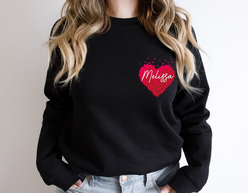 May include: Black sweatshirt with a pink heart design and the name "Melissa" written in white inside the heart.