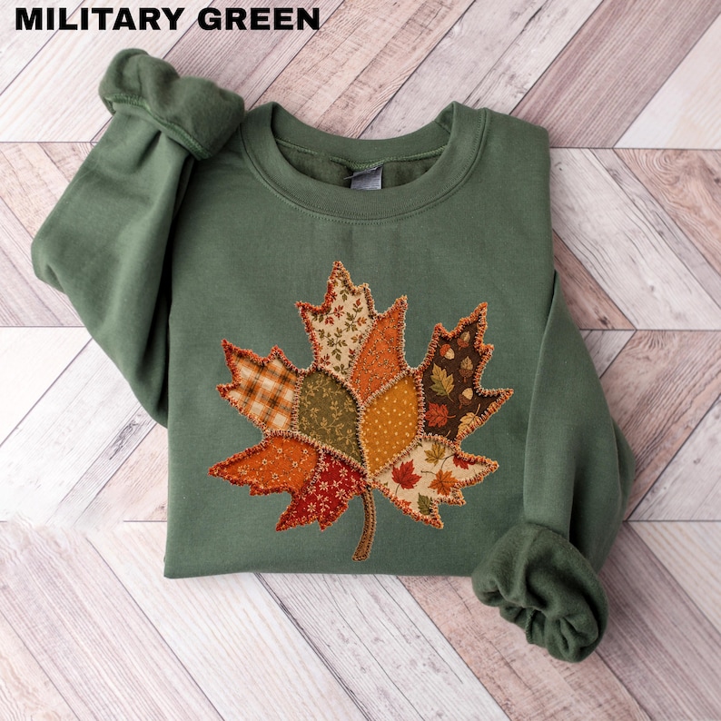 Fall season crewneck sweatshirt featuring a colorful autumn maple leaf graphic design printed on the front.