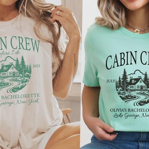 May include: Two short-sleeve crew neck t-shirts, one cream with green ink and one mint green with black ink. Both feature a graphic of a cabin in the woods with the text CABIN CREW, before I do, JULY 2025, OLIVIA'S BACHELORETTE, and Lake George, New York.