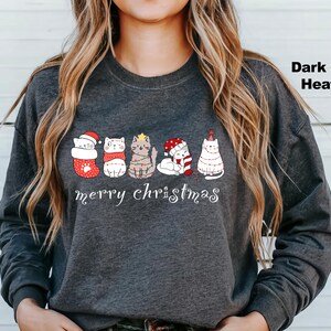 May include: Dark grey heather long-sleeve sweatshirt with a graphic of five cats wearing Christmas hats and the text "merry christmas".