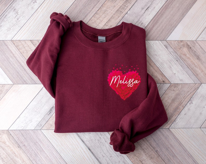 May include: Burgundy sweatshirt with a pink heart design and the name "Melissa" printed inside the heart.