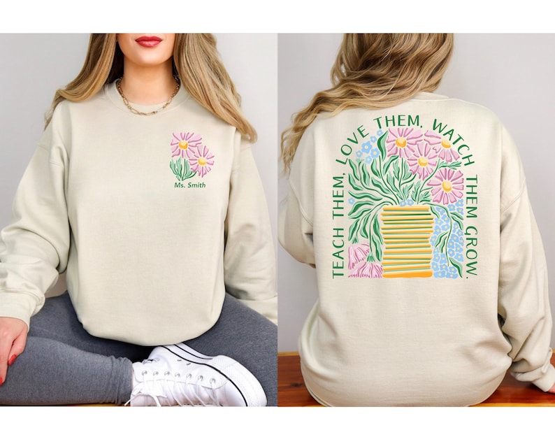 May include: Beige sweatshirt with a floral design. The front features a small bouquet of pink and yellow flowers with the text "Ms. Smith". The back displays a larger floral arrangement with the text "Teach them, love them, watch them grow."