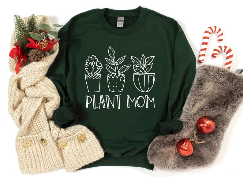 May include: A dark green sweatshirt with a white graphic of three potted plants and the text "PLANT MOM".