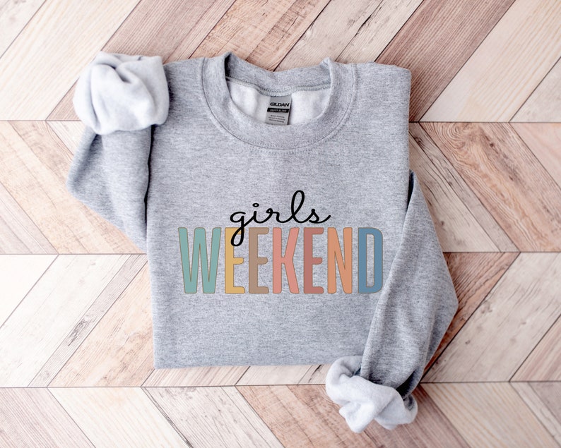 Peut inclure: Sweat-shirt gris avec le texte "girls weekend" en lettres color&eacute;es.