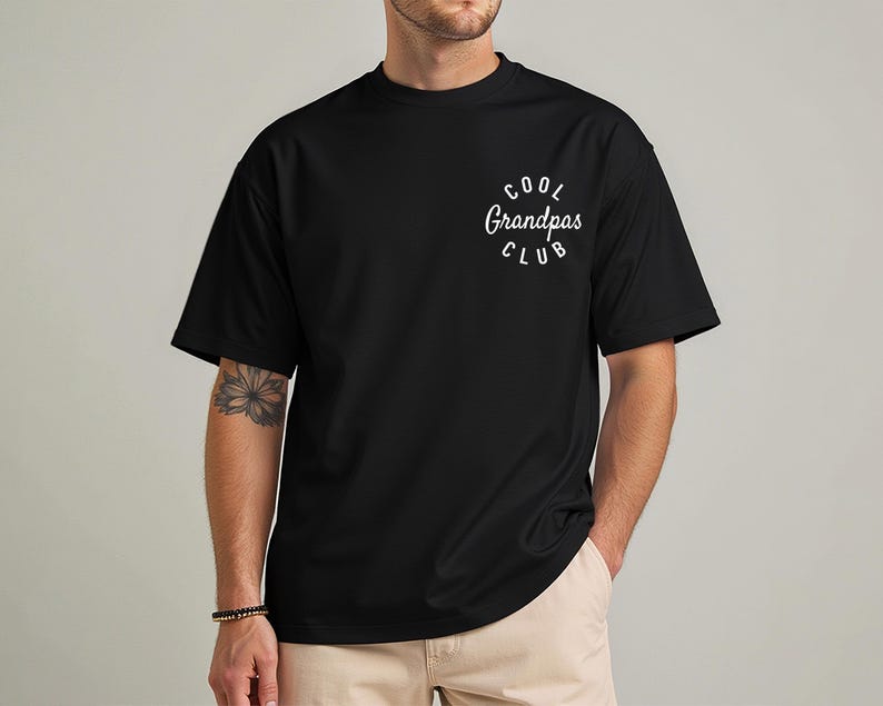 May include: Black t-shirt with the text "COOL GRANDPAS CLUB" in a white, curved font. The shirt is a solid black color and has short sleeves. The text is centered on the upper left chest area.