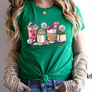 Pode incluir: Camiseta verde com um gr&aacute;fico de v&aacute;rias bebidas de caf&eacute; e ch&aacute; com flores e a palavra "morning" em uma das x&iacute;caras.