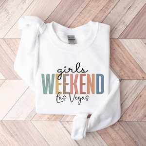 Peut inclure: Sweat-shirt blanc avec le texte "girls WEEKEND Las Vegas" en lettres majuscules color&eacute;es.