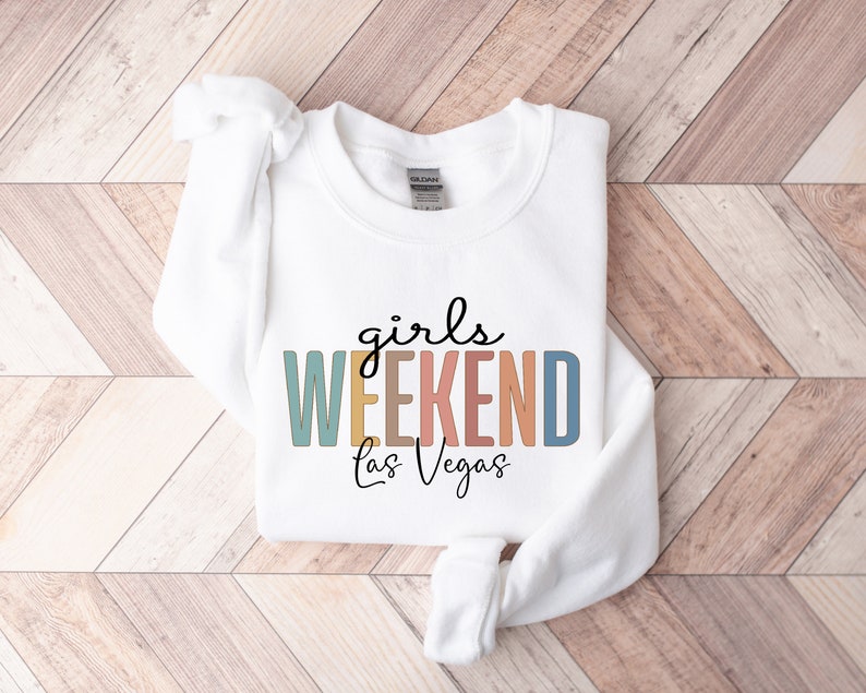 Peut inclure: Sweat-shirt blanc avec le texte "girls WEEKEND Las Vegas" en lettres majuscules color&eacute;es.