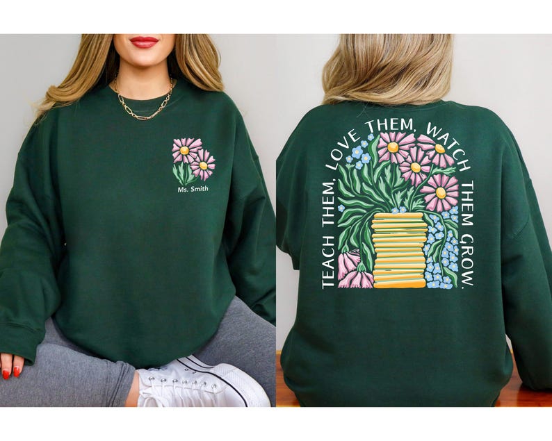 May include: Dark green sweatshirt with a floral design. The front features two pink and yellow flowers with the text "Ms. Smith". The back displays a larger floral arrangement with the text "TEACH THEM, LOVE THEM, WATCH THEM GROW."