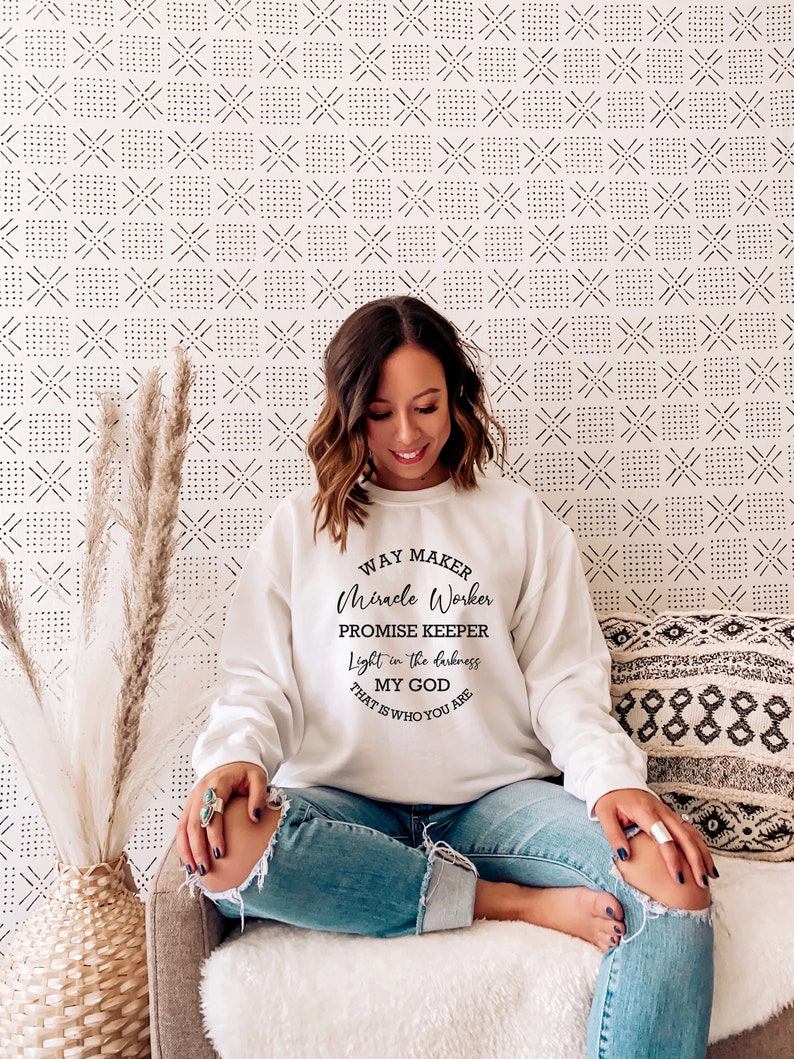 May include: White sweatshirt with a black graphic print that reads "Way Maker, Miracle Worker, Promise Keeper, Light in the darkness, My God That Is Who You Are".