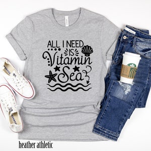 May include: Grey heather athletic t-shirt with black text that reads "All I need is Vitamin Sea" with a seashell, starfish, and waves.